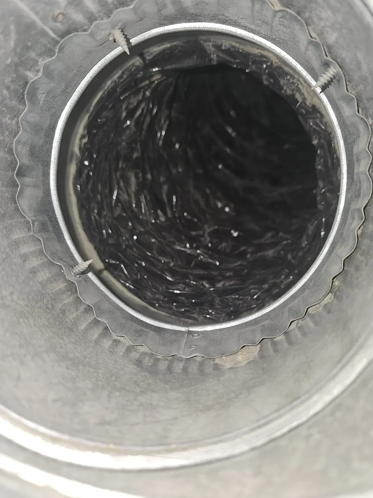 After: the same metal duct collar, clean, with the dark flexible duct inside