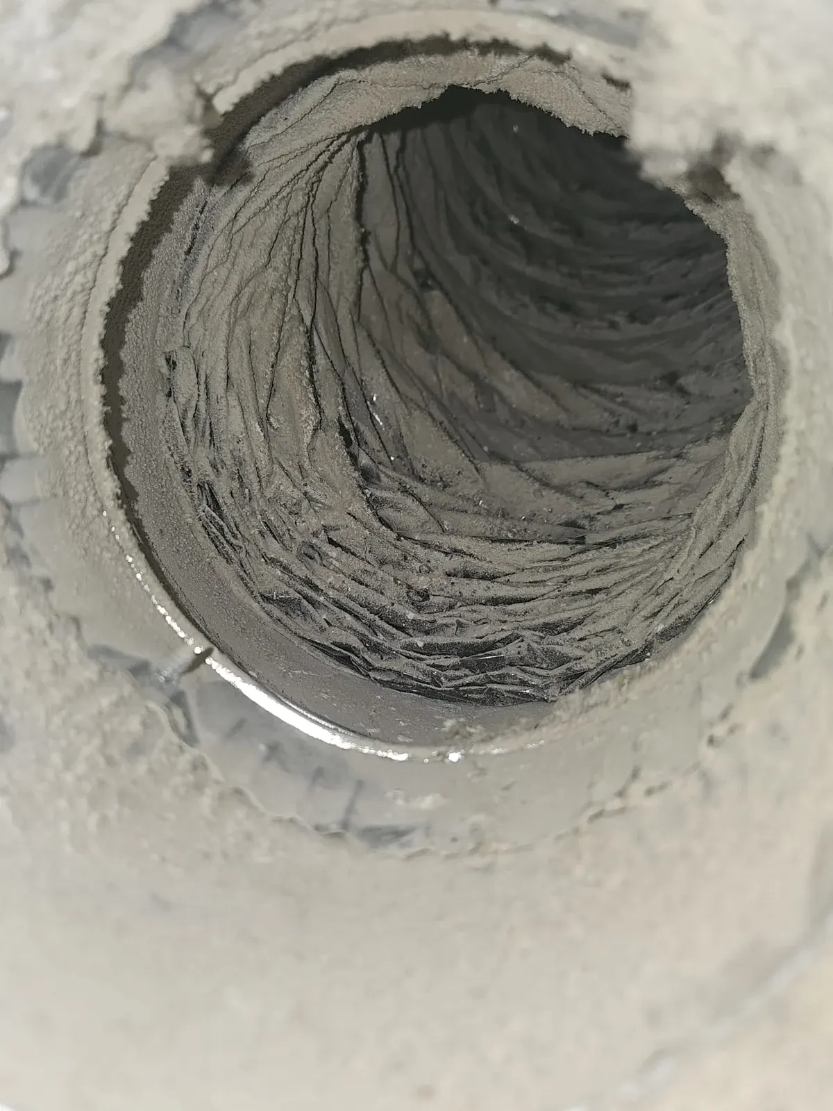 Before: metal duct collar and flexible duct coated in gray dust