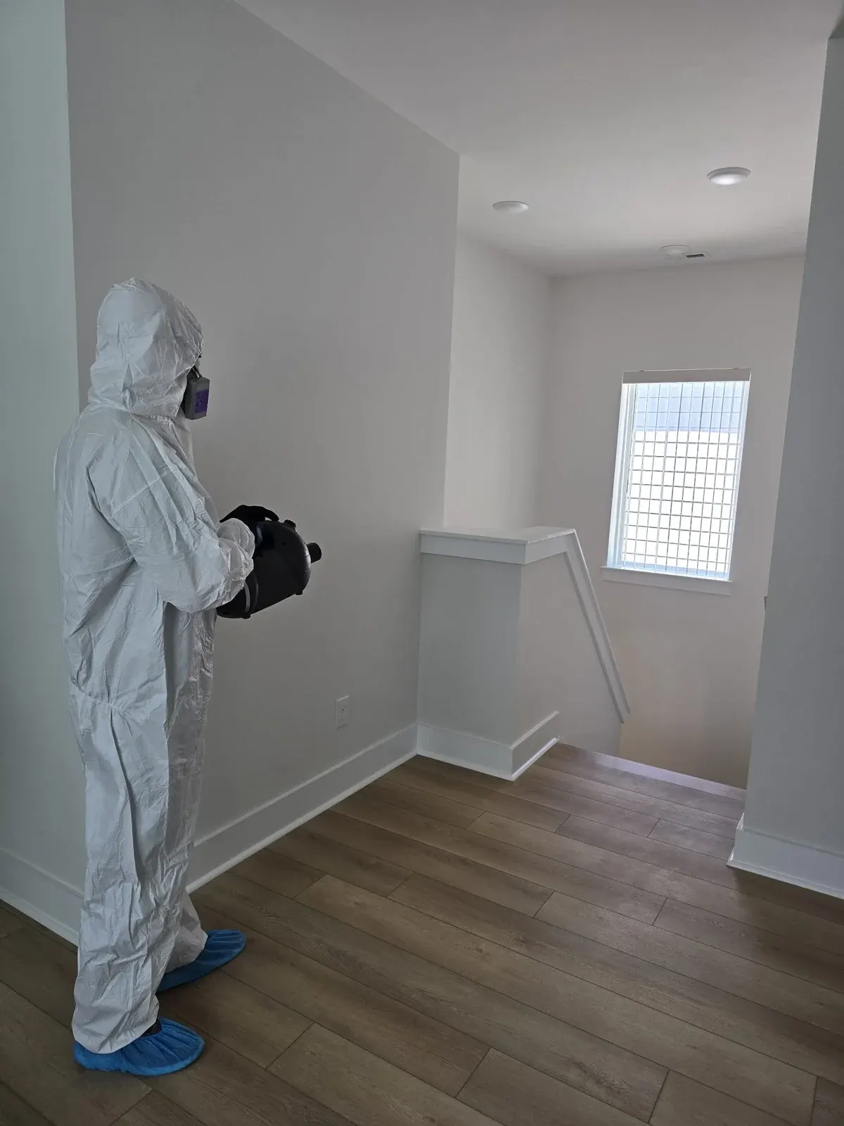 Technician in protective gear treating an empty room with a fogger