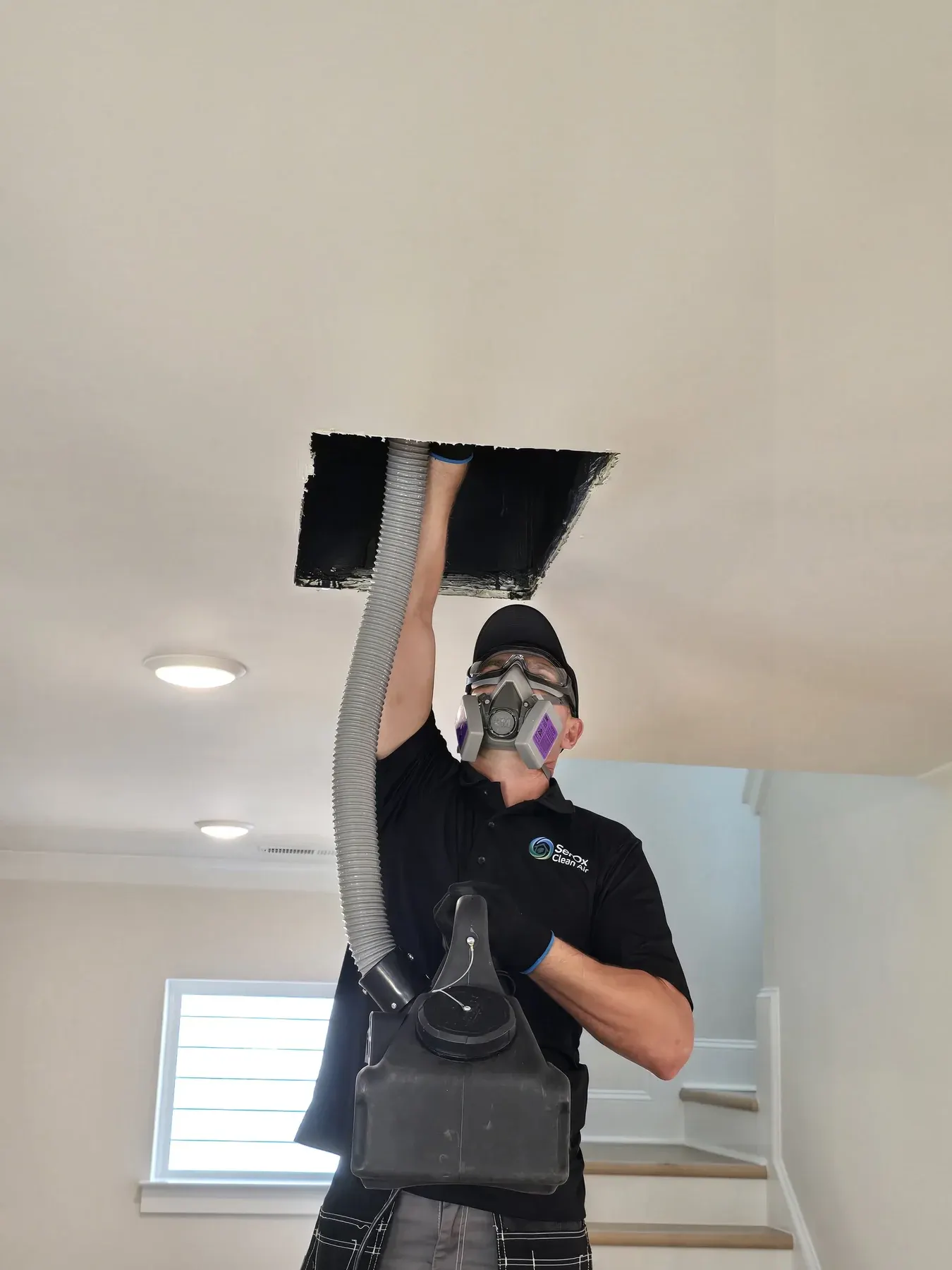 Low-angle view of a technician working under an open ceiling duct
